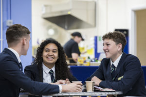 Two boys and One female sixth form students laughing and talking in the school canteen