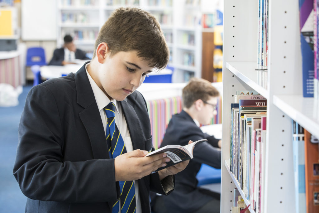 A boy reading a book in the school library