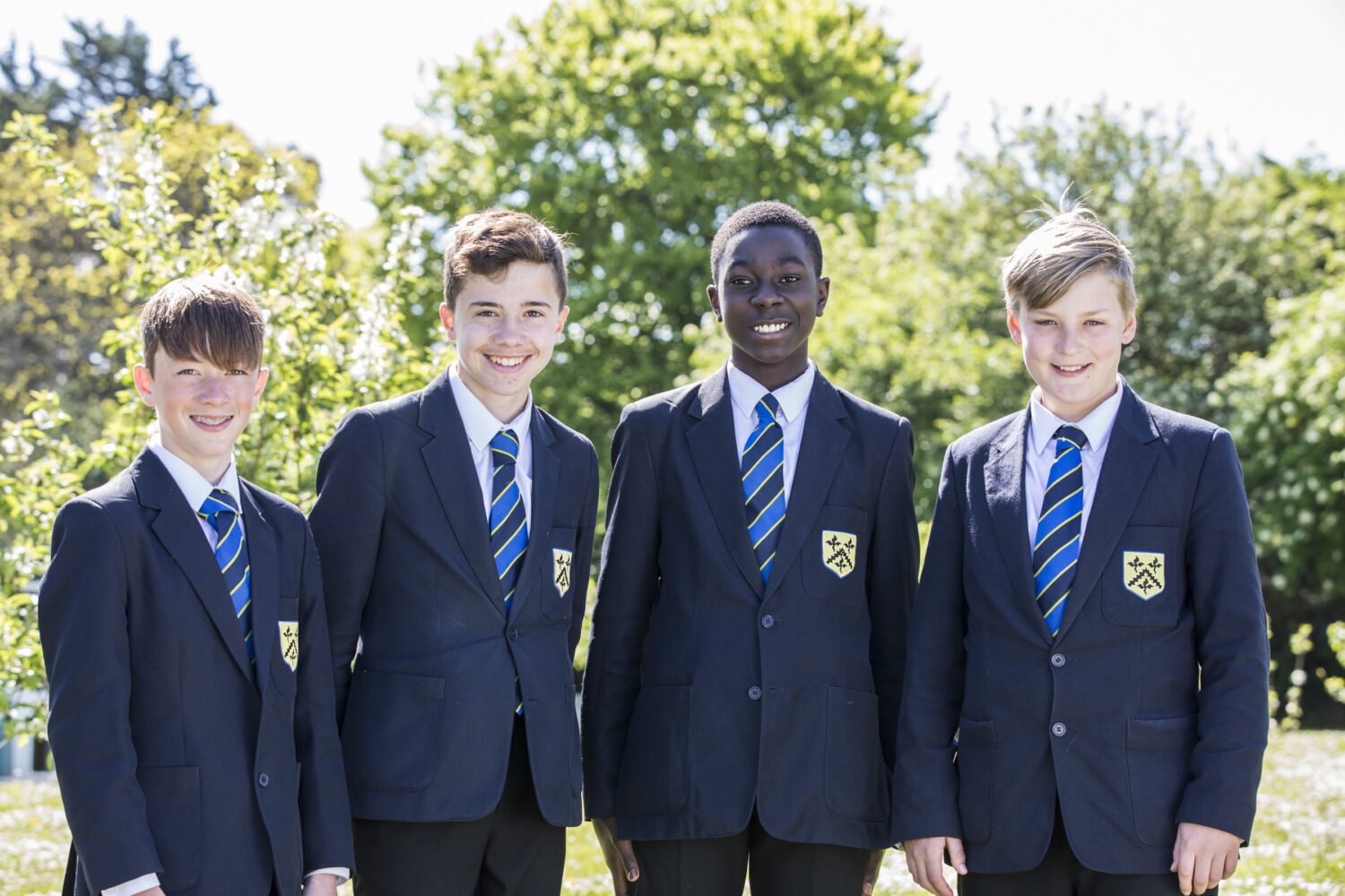 Four students from SJWMS stood in a leafy area wearing their school uniform