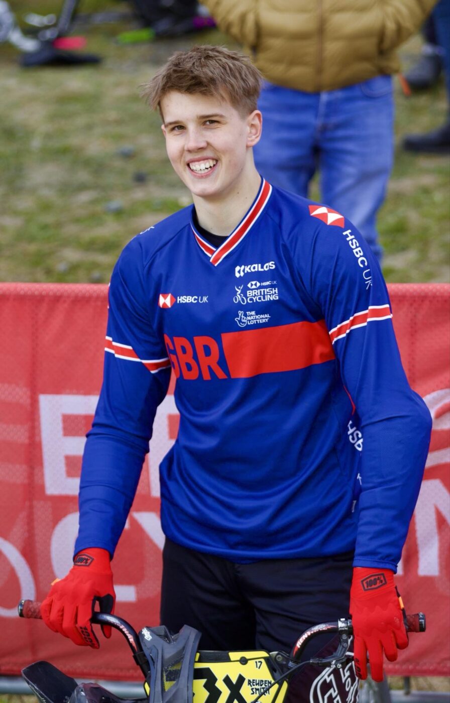 A young man named Reuben is pictured smiling, whilst dressed in his cycling gear, after having just finished a race.